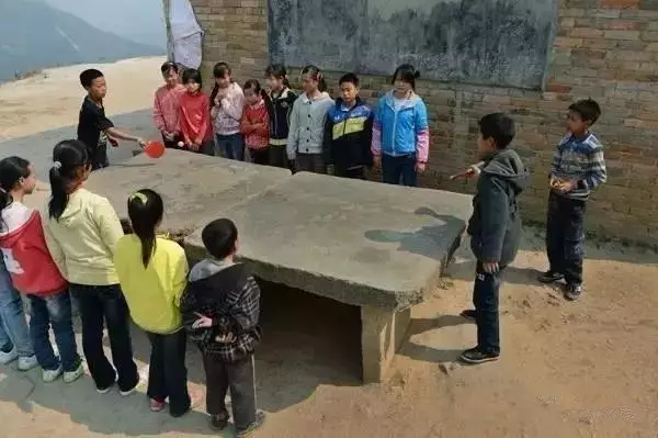 自制的乒乓球拍在两块水泥板上打乒乓球